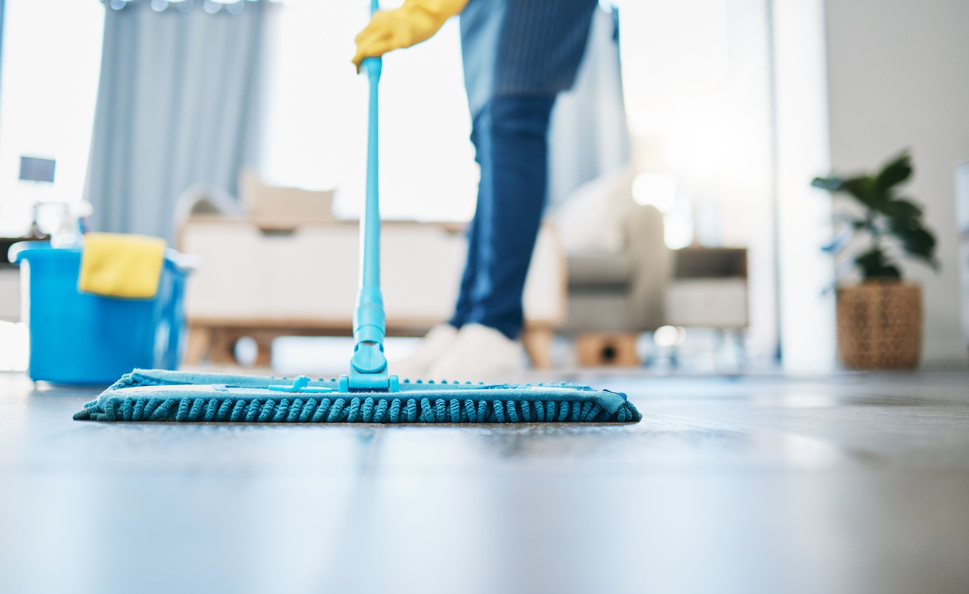 Housekeeping, cleaning and woman maid with a mop to clean the living room floor at a house. Female domestic worker, cleaner and housewife washing the ground for bacteria, dust or dirt in her home.